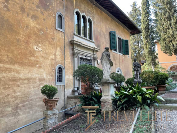 Усадебный дом в итальянском стиле с классическими статуями, ухоженными кустами и исторической архитектурой, представляющий элитную недвижимость для ценителей роскоши и комфорта.