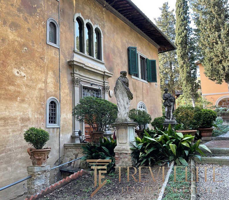 Усадебный дом в итальянском стиле с классическими статуями, ухоженными кустами и исторической архитектурой, представляющий элитную недвижимость для ценителей роскоши и комфорта.