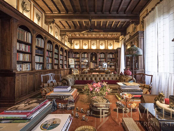 Роскошный домашний кабинет с деревянными книжными полками, антикварной мебелью и уютным мягким диваном, создающими атмосферу эксклюзивности и комфорта для высокого уровня жизни.