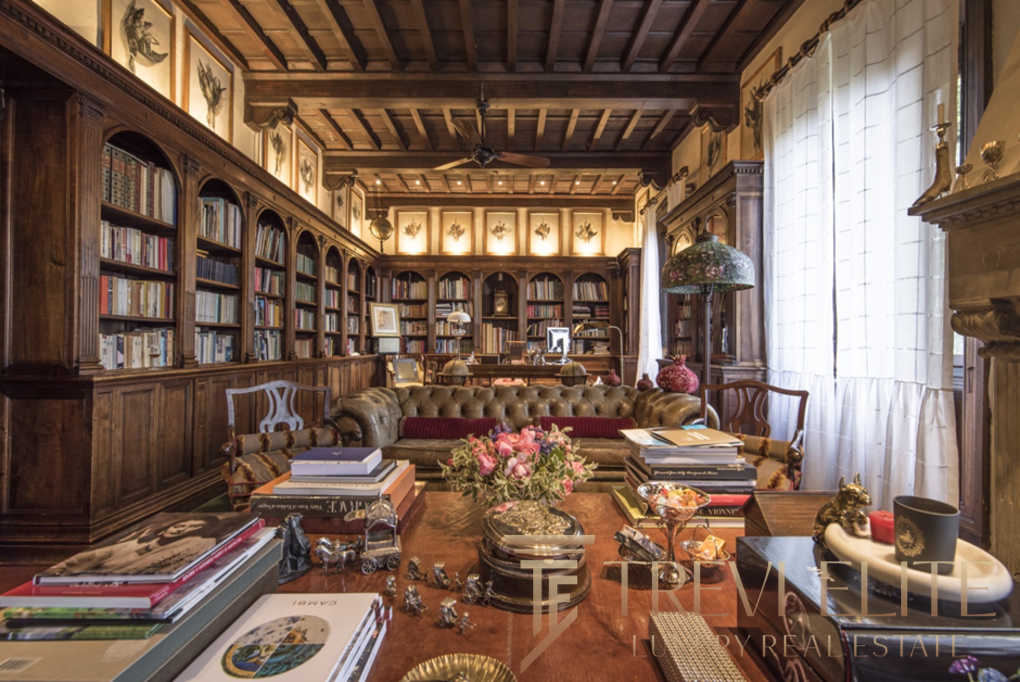 Роскошный домашний кабинет с деревянными книжными полками, антикварной мебелью и уютным мягким диваном, создающими атмосферу эксклюзивности и комфорта для высокого уровня жизни.