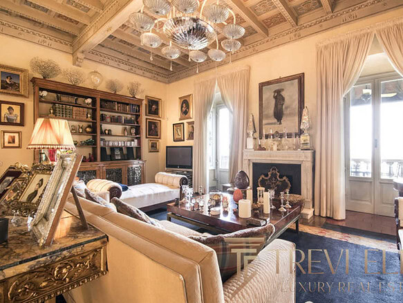 Роскошная гостиная в классическом стиле с богатой отделкой, камином, стенами, украшенными картинами и уютным освещением, создающая атмосферу уюта и элегантности.