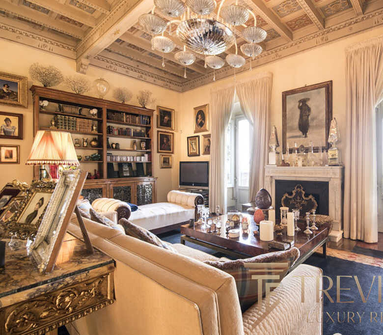 Роскошная гостиная в классическом стиле с богатой отделкой, камином, стенами, украшенными картинами и уютным освещением, создающая атмосферу уюта и элегантности.