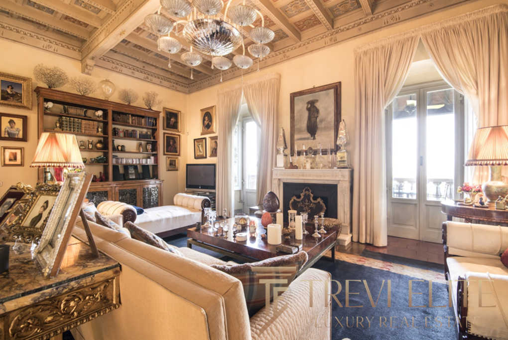 Роскошная гостиная в классическом стиле с богатой отделкой, камином, стенами, украшенными картинами и уютным освещением, создающая атмосферу уюта и элегантности.