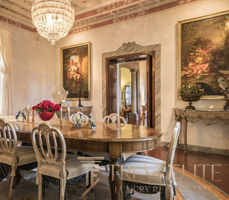 Роскошная столовая с антикварной мебелью и богатым декором, просторные окна с тяжелыми шторами, изысканное освещение, идеальное пространство для эксклюзивных мероприятий и семейных ужинов.