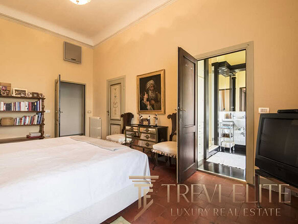 Уютная спальня с классической мебелью и выходом на балкон, создающая атмосферу уюта и роскоши в элитной недвижимости.