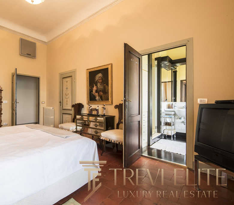 Уютная спальня с классической мебелью и выходом на балкон, создающая атмосферу уюта и роскоши в элитной недвижимости.