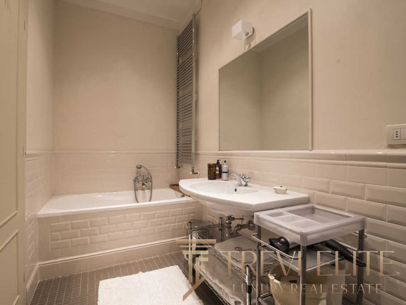 Элегантная современная ванная комната с белой плиткой и стильной сантехникой, идеально подходящая для роскошного жилья. Великолепная отделка и уютная атмосфера создают ощущение комфорта и изыска.