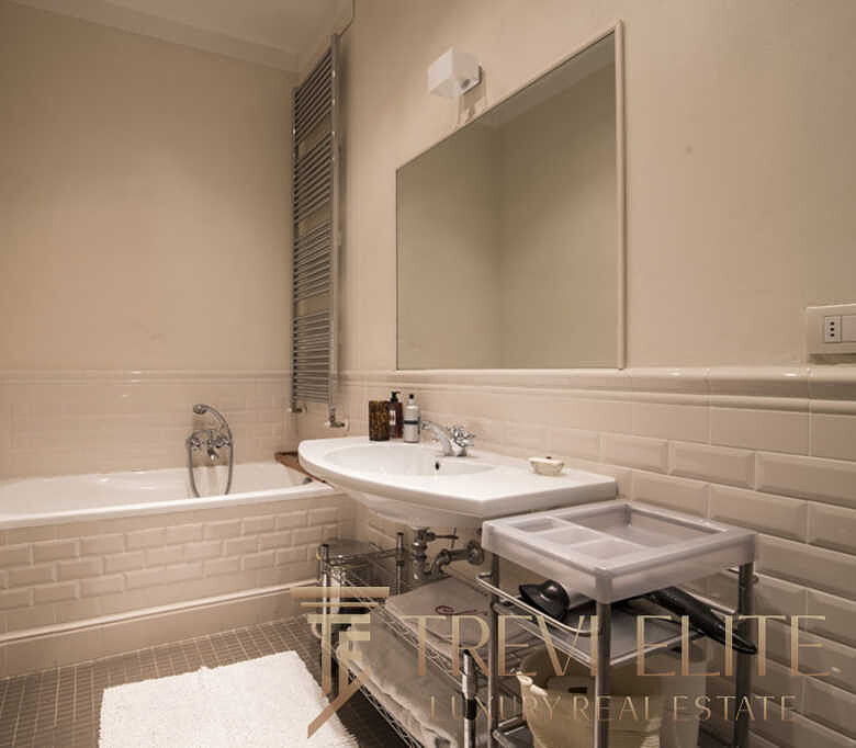 Элегантная современная ванная комната с белой плиткой и стильной сантехникой, идеально подходящая для роскошного жилья. Великолепная отделка и уютная атмосфера создают ощущение комфорта и изыска.