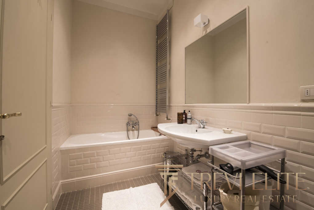 Элегантная современная ванная комната с белой плиткой и стильной сантехникой, идеально подходящая для роскошного жилья. Великолепная отделка и уютная атмосфера создают ощущение комфорта и изыска.