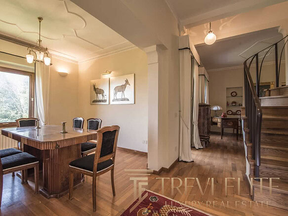 роскошная гостиная с деревянной мебелью и ярким освещением, классический интерьер с художественными изображениями и уютной атмосферой элитной недвижимости.