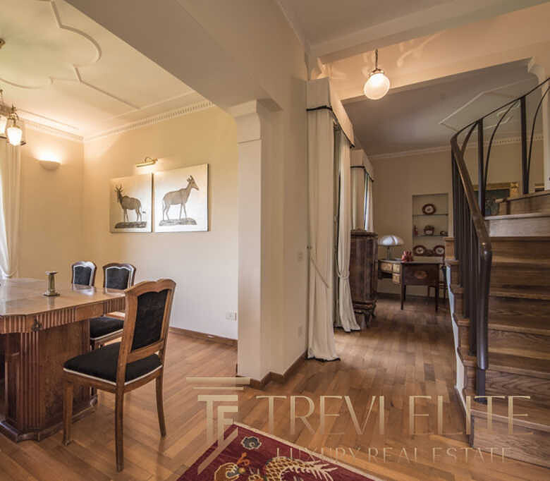 роскошная гостиная с деревянной мебелью и ярким освещением, классический интерьер с художественными изображениями и уютной атмосферой элитной недвижимости.