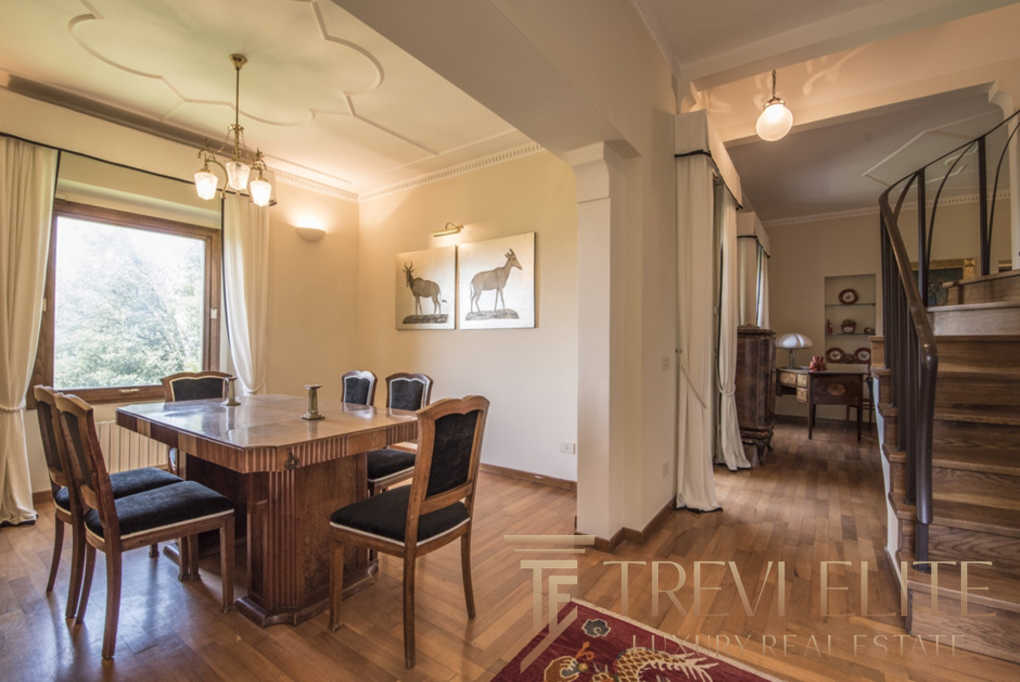 роскошная гостиная с деревянной мебелью и ярким освещением, классический интерьер с художественными изображениями и уютной атмосферой элитной недвижимости.