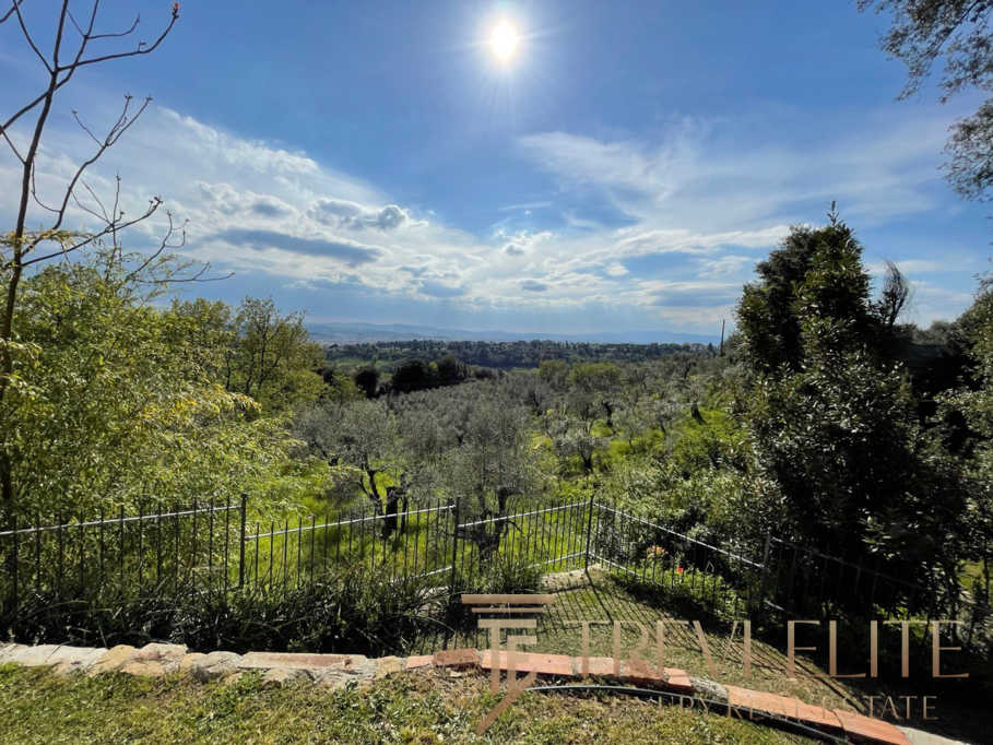 Удивительный вид на зеленый сад с деревьями и облаками, открывающийся с террасы в живописном итальянском районе. Идеально подходит для роскошного отдыха и эксклюзивных недвижимости.