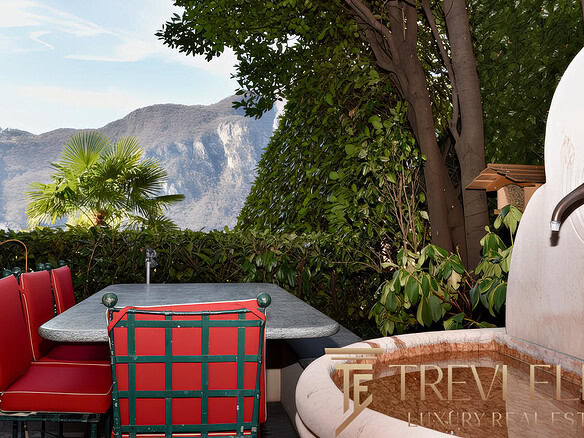 Растения уличный двор с видом на горы, обеденный стол с красными стульями и фонтан, создающий атмосферу уединения и покоя у природы.