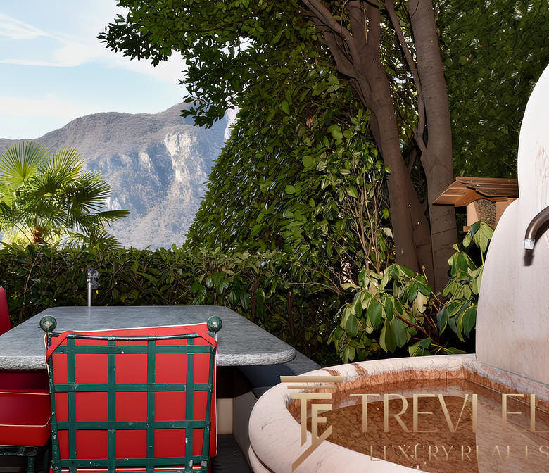 Растения уличный двор с видом на горы, обеденный стол с красными стульями и фонтан, создающий атмосферу уединения и покоя у природы.