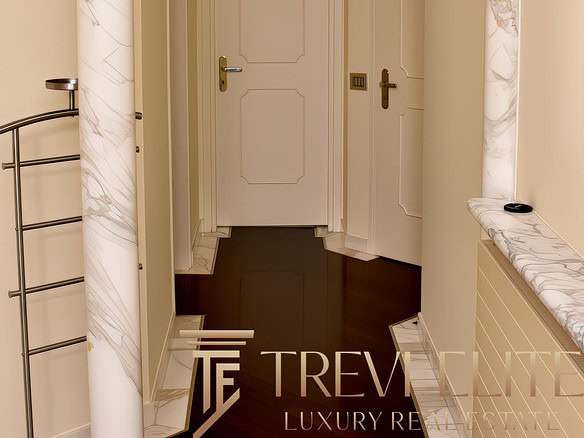 Элегантный коридор в классическом стиле с мраморными колоннами и светильниками, окрашенными в мягкие светлые оттенки, создает атмосферу роскоши и уюта.