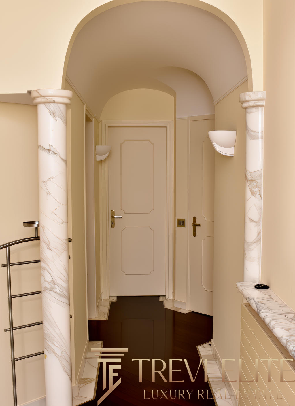 Элегантный коридор в классическом стиле с мраморными колоннами и светильниками, окрашенными в мягкие светлые оттенки, создает атмосферу роскоши и уюта.