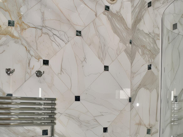 Роскошная ванная комната с мраморными стенами и современной сантехникой, включает металлический полотенцесушитель и встроенные светильники, подчеркивающие элегантность интерьера.