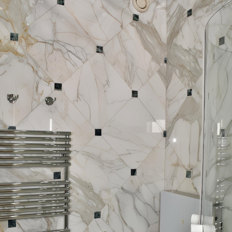 Роскошная ванная комната с мраморными стенами и современной сантехникой, включает металлический полотенцесушитель и встроенные светильники, подчеркивающие элегантность интерьера.
