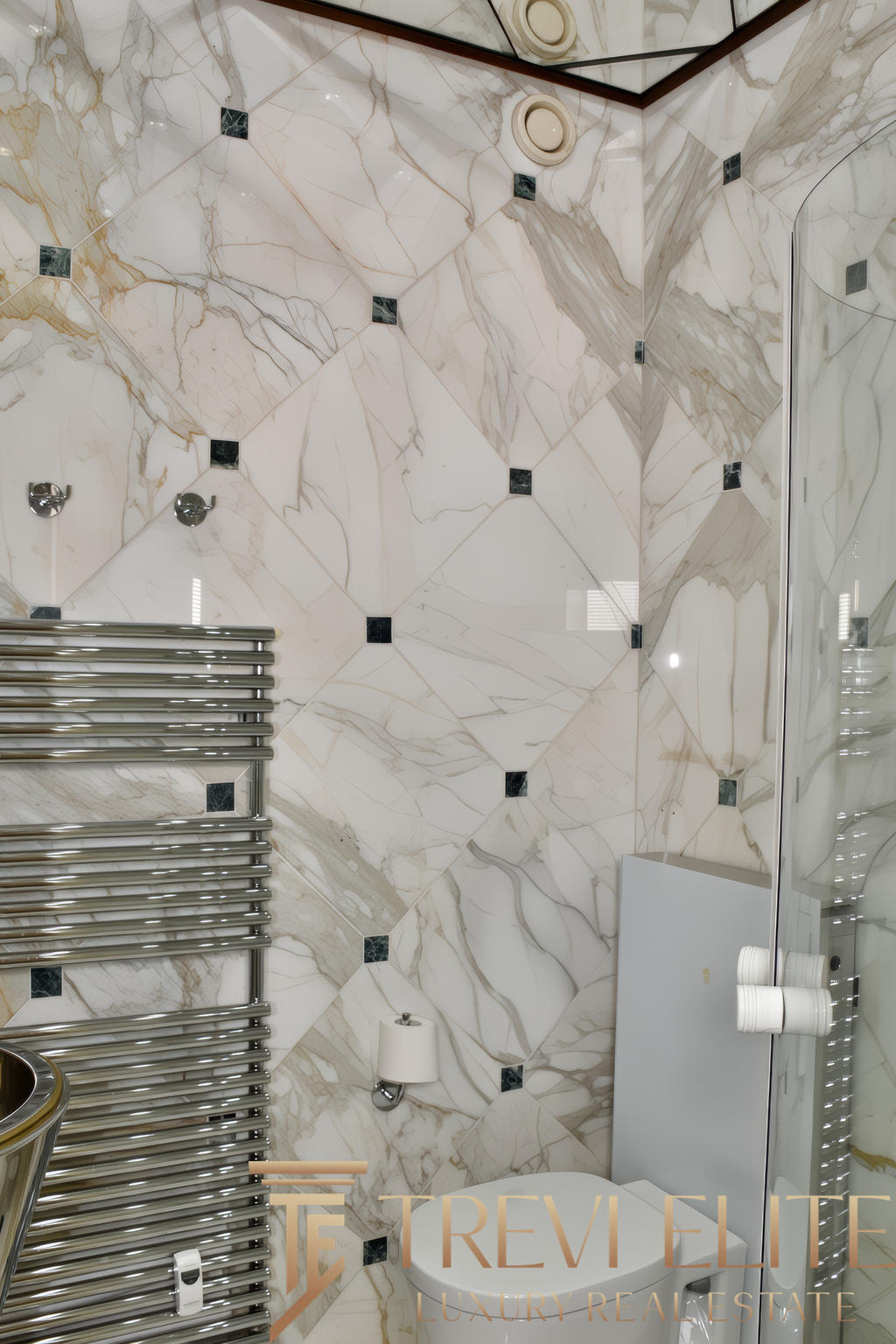 Роскошная ванная комната с мраморными стенами и современной сантехникой, включает металлический полотенцесушитель и встроенные светильники, подчеркивающие элегантность интерьера.