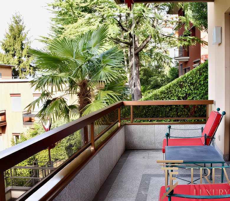 Зеленый пейзаж с деревьями и пальмами за уютным балконом современного жилого комплекса.