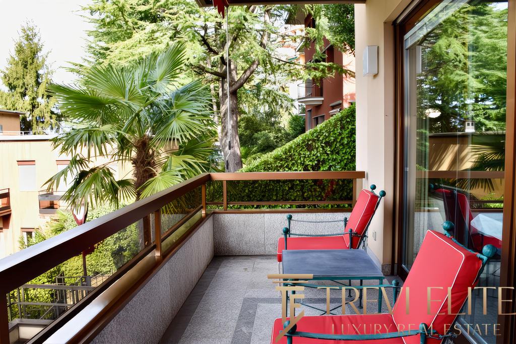 Зеленый пейзаж с деревьями и пальмами за уютным балконом современного жилого комплекса.