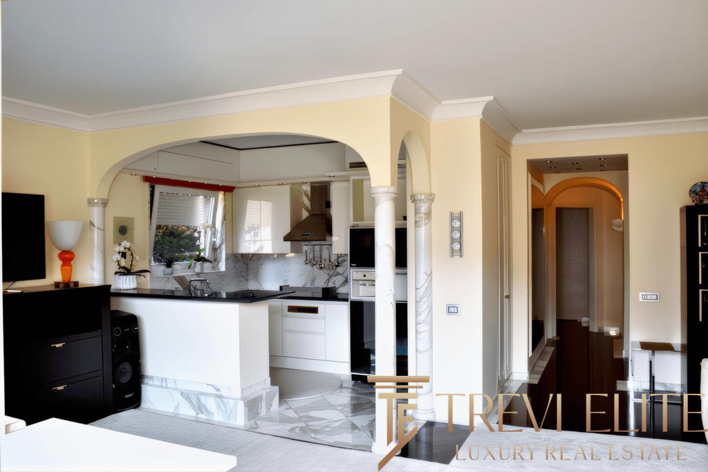 Современная кухня с насыщенными белыми и мраморными элементами, уютным освещением и просторным интерьером в стиле роскоши, идеально подходящая для комфортной жизни и встреч с друзьями.