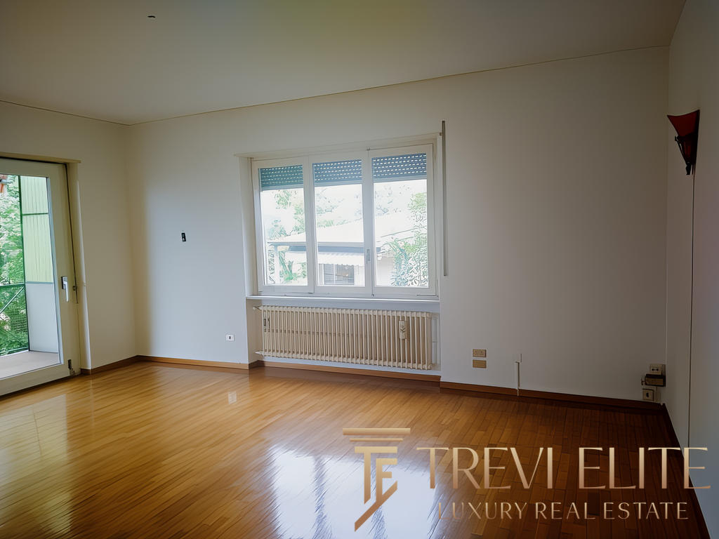 Современная уютная гостиная с большими окнами и деревянным полом, светлые стены, выход на балкон, идеально подходит для комфортной жизни.