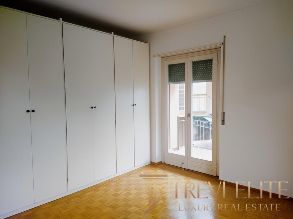 Просторная комната с белыми встроенными шкафами и большим балконным стеклопакетом. Светлая и уютная, идеально подойдет для комфортной жизни.