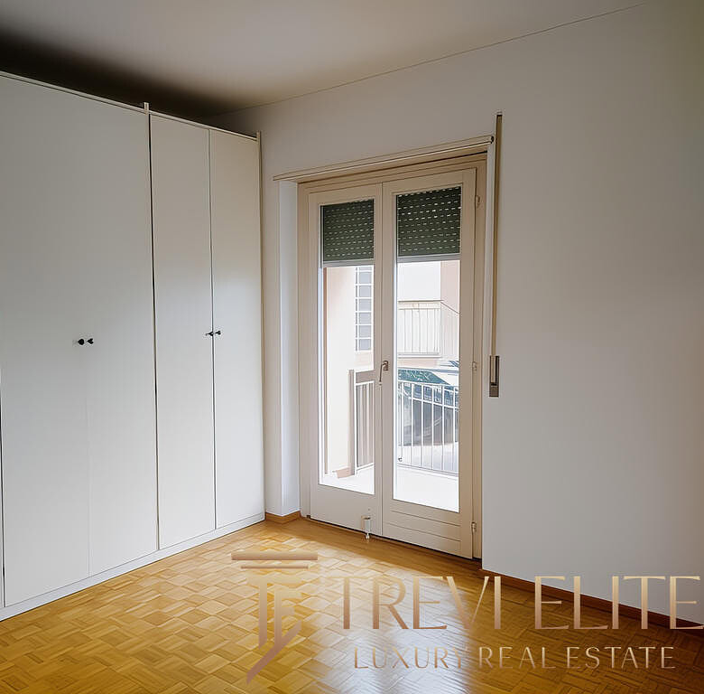 Просторная комната с белыми встроенными шкафами и большим балконным стеклопакетом. Светлая и уютная, идеально подойдет для комфортной жизни.