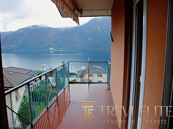 Вид с балкона на озеро и горы, уютное пространство для отдыха, современные материалы, спокойная атмосфера.