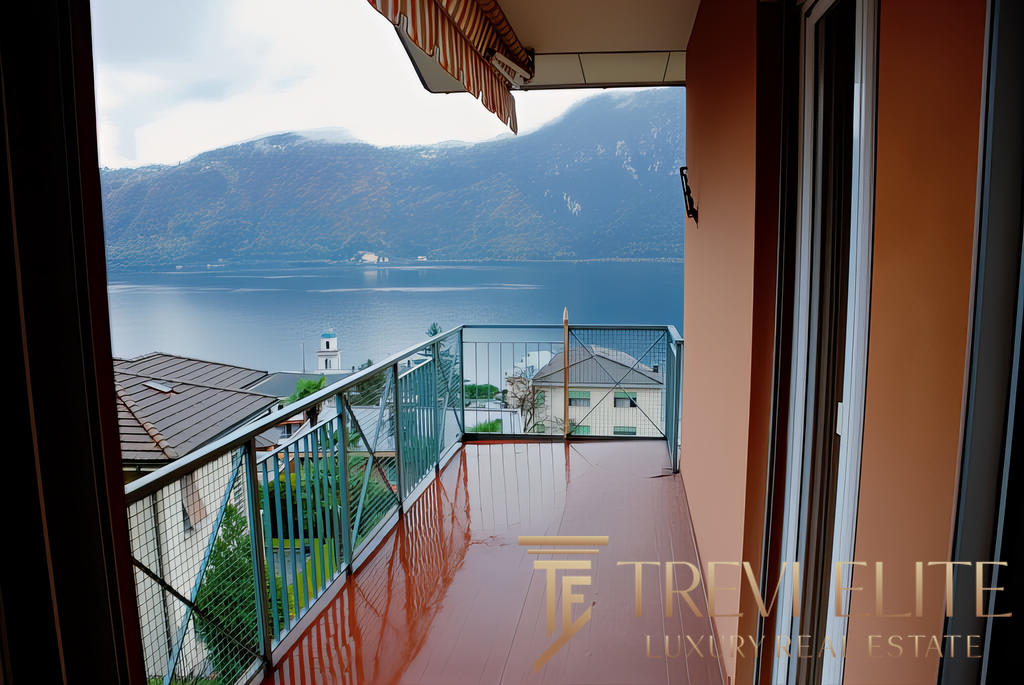 Вид с балкона на озеро и горы, уютное пространство для отдыха, современные материалы, спокойная атмосфера.