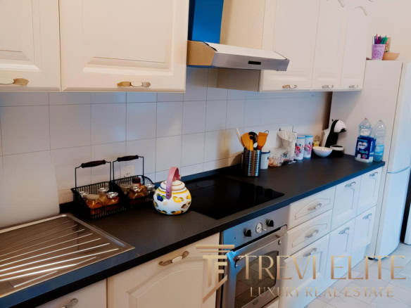 Кухонная мебель с бытовой техникой и принадлежностями в современной кухне. Желтые и голубые детали на фоне светлых шкафов. Стильный дизайн интерьера кухни.