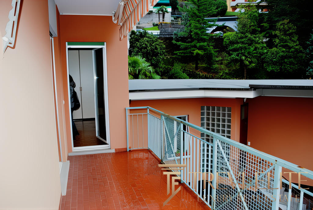 Окно балкона с видом на зелень и современные жилые комплексы, стильный интерьер, уютная уютная терраса, дощатый пол, патио, уютная зона отдыха на свежем воздухе.