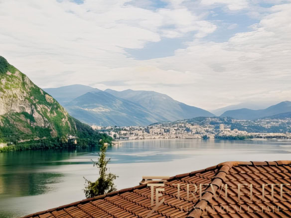 Красивая панорама озера и гор на фоне древних зданий и красной черепичной крыши. Идеальное место для элитной недвижимости и инвестиций в жилье с великолепным видом.