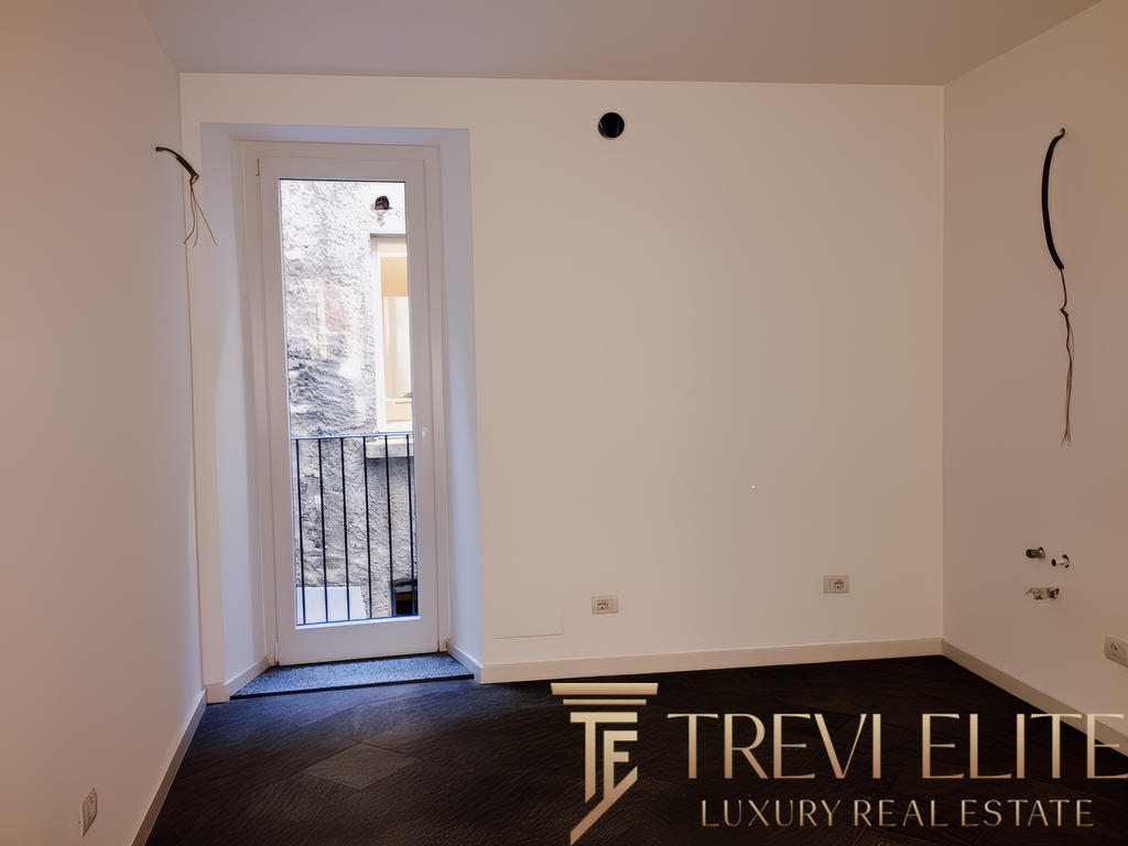 Внутренний интерьер пустой комнаты с белыми стенами, выходом на балкон и видеоконструкциями, готовыми для ремонта и модернизации, в современном жилом комплексе.