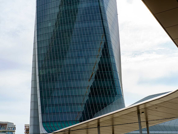 Современное стеклянное офисное здание, отражающее небоскребы и городской пейзаж, представляет архитектурную элиту и деловой центр города.