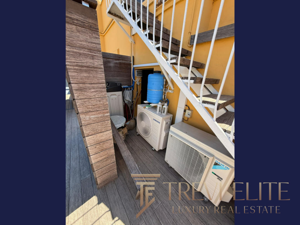 Крупный план кондиционера и системы охлаждения на балконе с лестницей и деревянным настилом, характерный для элитных апартаментов в Италии, предлагаемых агентством Треви Элит.
