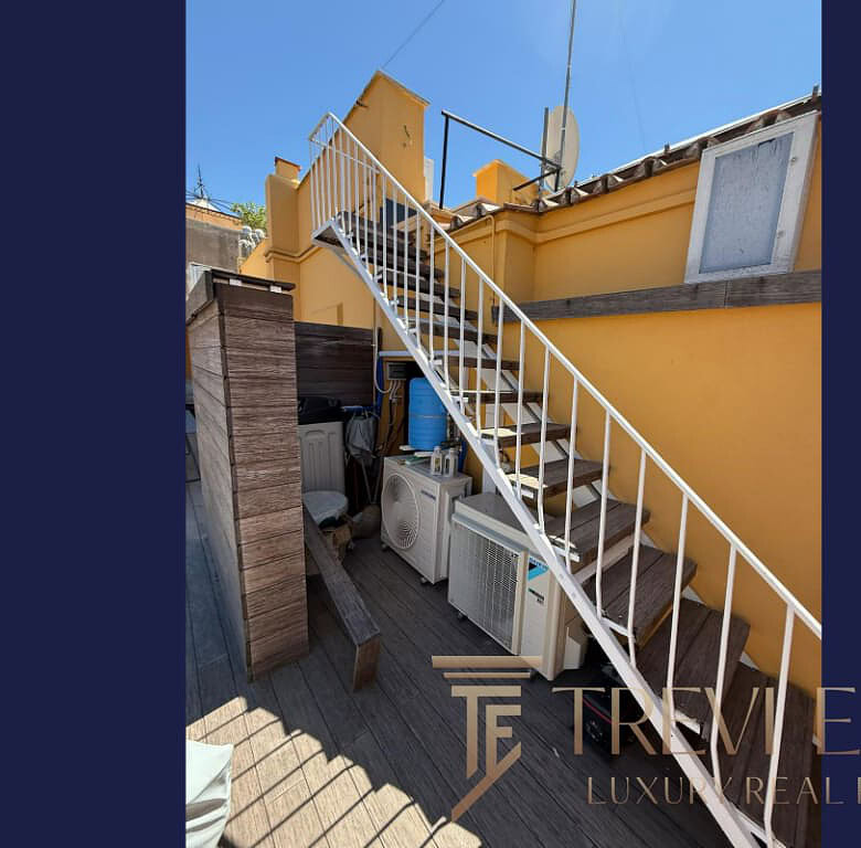 Производственная территория с внешней лестницей и солнечной атмосферой у жёлтой стены. Идеально подходит для элитной недвижимости в Италии и по всему миру, предлагая эксклюзивные объекты с высокой ценностью.