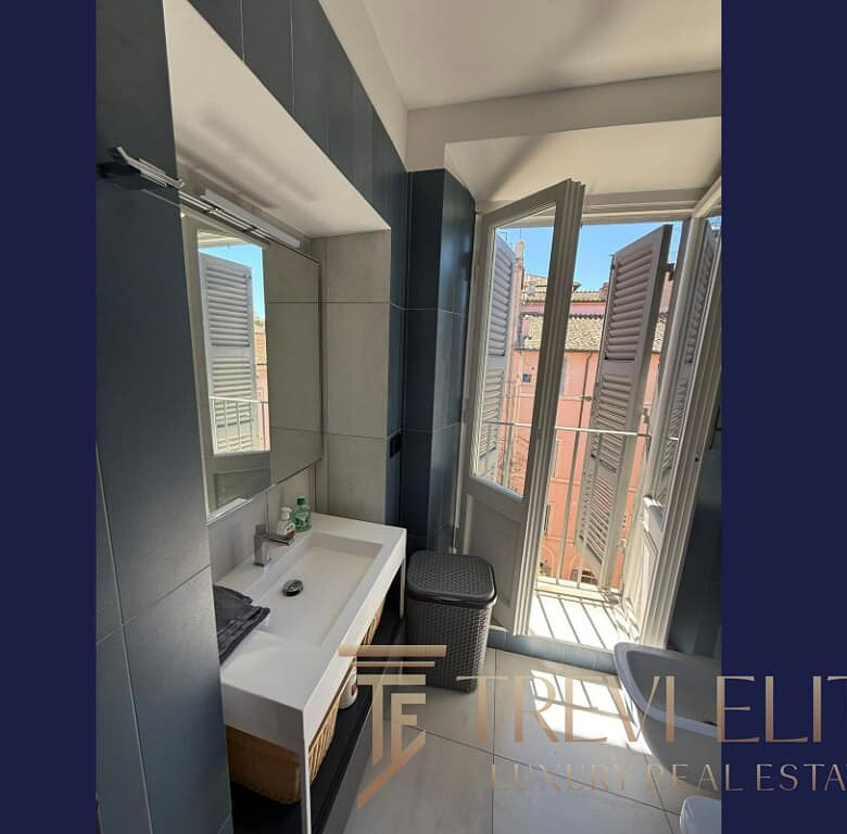 Современная ванная комната с большим окном и ванной дверью, оформление в светлых тонах, уютная и стильная обстановка, идеально подходит для роскошной недвижимости в Италии.