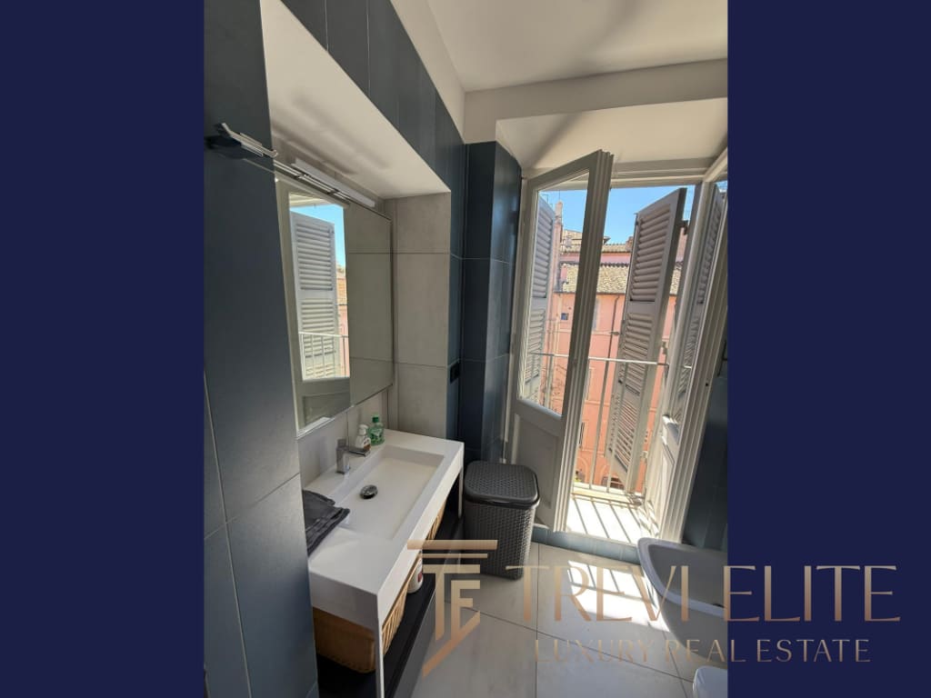 Современная ванная комната с большим окном и ванной дверью, оформление в светлых тонах, уютная и стильная обстановка, идеально подходит для роскошной недвижимости в Италии.