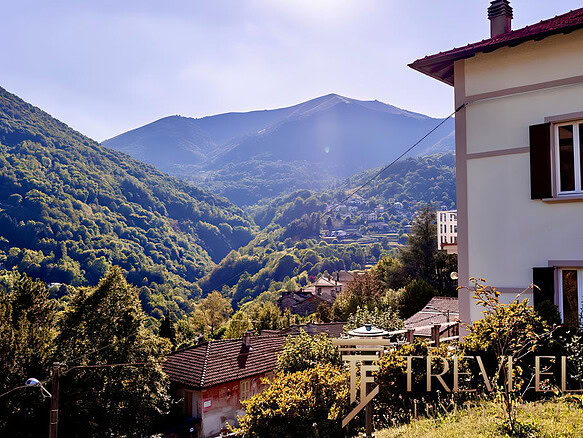 Уютный дом на фоне живописных горных пейзажей, окруженный зеленью и природой, идеально подходит для комфортного проживания и инвестиций в загородную недвижимость.