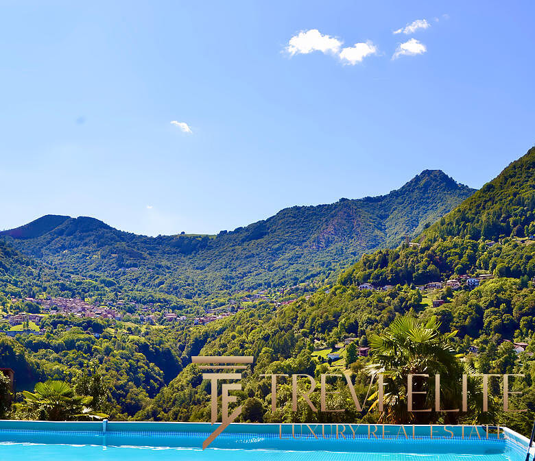 Роскошный вид на зелёные горы и живописные пейзажи с бассейном на переднем плане, идеальный для элитной недвижимости и отдыха на природе.