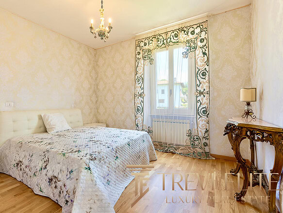 Комната с уютной кроватью и элегантным дизайном в стиле классика, с золотистыми стенами, цветочными шторами и декоративной мебелью. Идеально подходит для комфортного проживания.