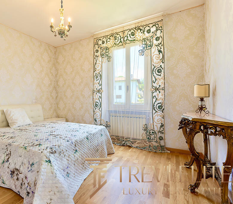 Комната с уютной кроватью и элегантным дизайном в стиле классика, с золотистыми стенами, цветочными шторами и декоративной мебелью. Идеально подходит для комфортного проживания.