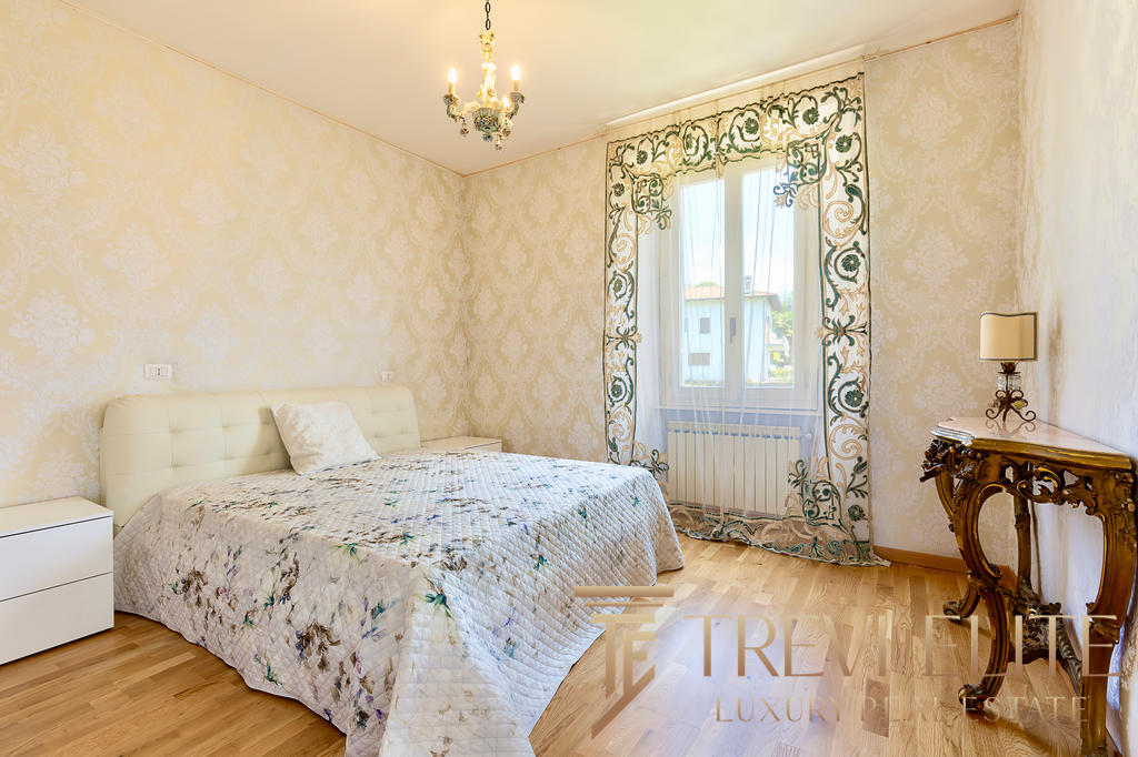 Комната с уютной кроватью и элегантным дизайном в стиле классика, с золотистыми стенами, цветочными шторами и декоративной мебелью. Идеально подходит для комфортного проживания.