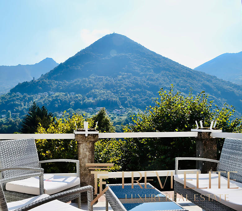 Горы на фоне, уютная терраса с креслами, панорамный вид на природу, элитная недвижимость, живописный пейзаж, роскошное жилье, Треви Элит, агентство недвижимости, элитные дома, золотая осень, отдых на природе, эксклюзивный интерьер, недвижимость в горах, панорамные окна, уютный балкон, высокое качество, комфорт и стиль.