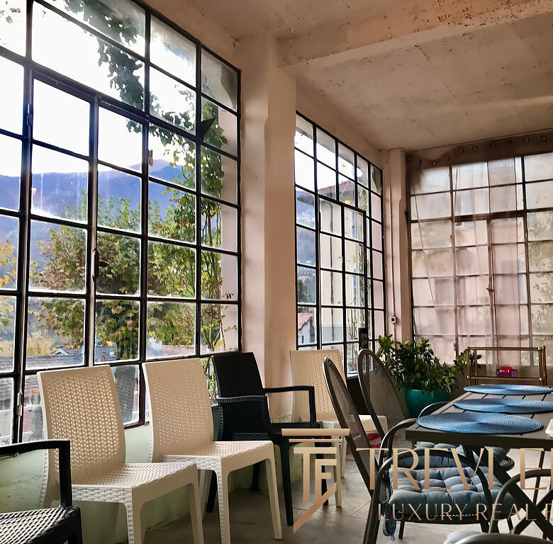 Современная зона отдыха в офисе или кафе с большими панорамными окнами и уютной атмосферой, идеальной для встреч и переговоров.