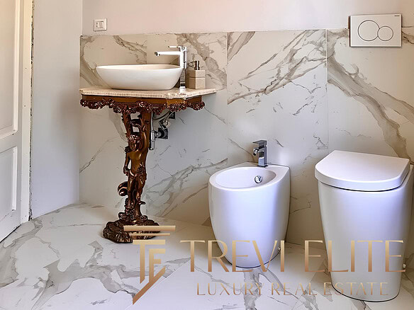 Мраморные стены и стильное дизайнерское биде в современной ванной комнате. Элегантное сочетание классики и модерна, создающее атмосферу роскоши и уюта в жилом помещении.