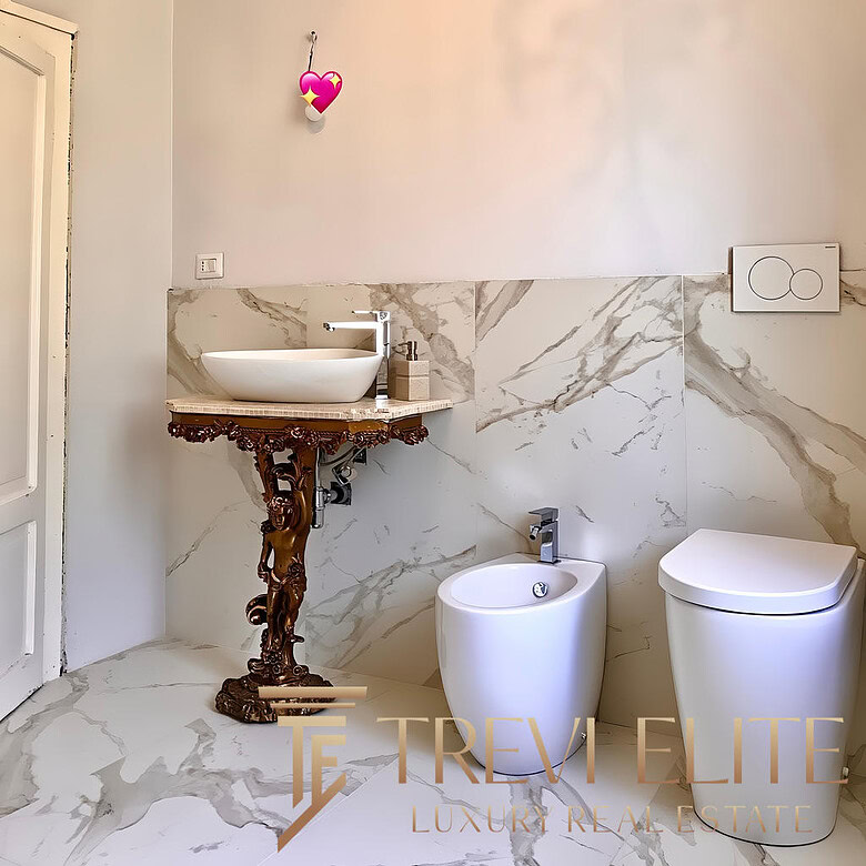 Мраморные стены и стильное дизайнерское биде в современной ванной комнате. Элегантное сочетание классики и модерна, создающее атмосферу роскоши и уюта в жилом помещении.
